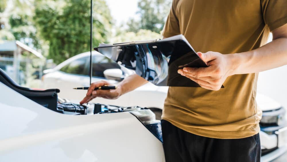 Man fills out a car insurance form after a car accident. Compreh